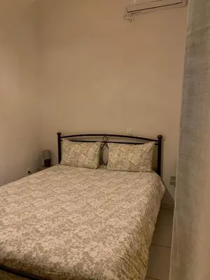 a bed in a white room with a bedspread and pillows at Gina's cozy home in Athens