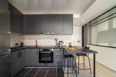 a kitchen with black cabinets and a table with stools at Kolonaki Square Central Penthouse in Athens