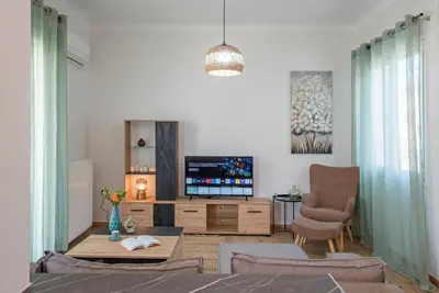 a living room with a flat screen tv and a chair at Acropolis view apt in Koukaki in Athens