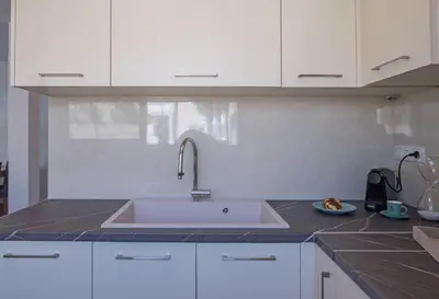 a kitchen with a sink and white cabinets at Acropolis view apt in Koukaki in Athens