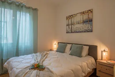 a bedroom with a large white bed and a window at Acropolis view apt in Koukaki in Athens