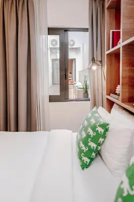 a white bed with a pillow and a window at Next door Athens in Athens