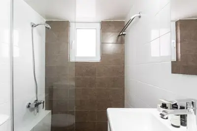 a white bathroom with a shower and a sink at Comfy 1BR Apartment in Ampelokipoi by UPSTREET in Athens