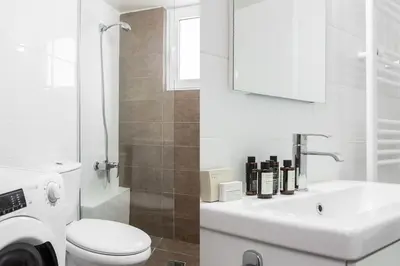 a white bathroom with a toilet and a sink at Comfy 1BR Apartment in Ampelokipoi by UPSTREET in Athens