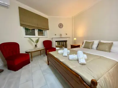 a bedroom with a bed with two chairs and a fireplace at Nikos Apartment in Spáta