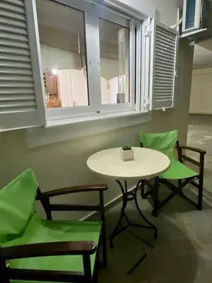 a table and chairs in a room with a table and windows at Nikos Apartment in Spáta