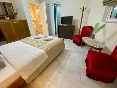 a bedroom with a large bed and a red chair at Nikos Apartment in Spáta