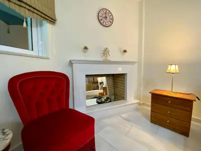 a living room with a red chair and a fireplace at Nikos Apartment in Spáta