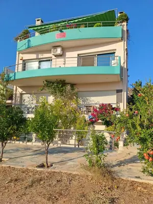 a building with a balcony and some trees and flowers at Sunset at Cape Sounio in Sounio
