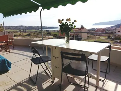 a table with chairs and a vase of flowers on a balcony at Sunset at Cape Sounio in Sounio