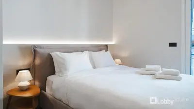 a large white bed with two towels on top of it at Muse Apartment by LobbySquare in Athens