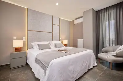 a bedroom with a large white bed and a chair at CW Athens Riviera Suite in Athens