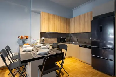 a kitchen with a table with chairs and a black refrigerator at Zephyr 3-Bedroom Apartment in Athens in Athens