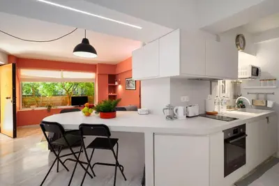 a kitchen with white cabinets and a table and chairs at Gly3 65m2 sunshine oasis in Glyfada in Athens