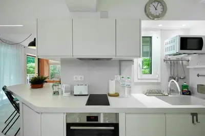 a kitchen with white cabinets and a clock on the wall at Gly3 65m2 sunshine oasis in Glyfada in Athens