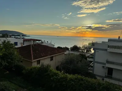 a view of the ocean with buildings and a sunset at Traditional Seaview Maisonette in Saronida