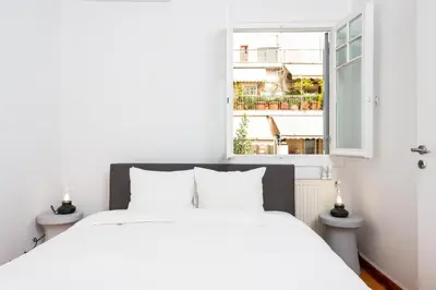a bedroom with a white bed and a window at zen penthouse in exarchia in Athens