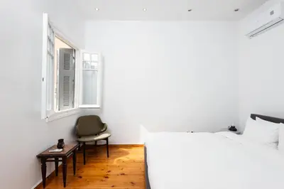 a bedroom with a bed and a chair and a window at zen penthouse in exarchia in Athens