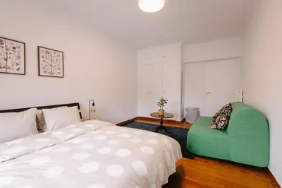 a bedroom with a bed and a green chair at ZEN Sofokleous in psiri in Athens