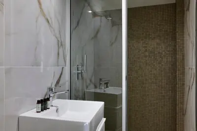 a white bathroom with a sink and a mirror at Hestia - Kolokotroni 23 in Athens