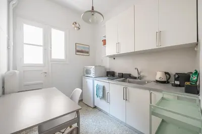 a kitchen with white cabinets and a sink and a table at Zen Exaricha in Athens