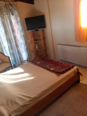 a bedroom with a bed with a television on the wall at Suburbs Georgia's loft in country side 15' from the Airport in Paianía