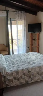 a bedroom with a bed with a television and a window at Suburbs Georgia's loft in country side 15' from the Airport in Paianía