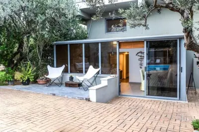a house with glass doors and white chairs on a patio at Varkiza Minimal Residence-5minSea in Vari