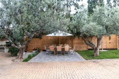 a patio with a table and chairs and trees at Varkiza Minimal Residence-5minSea in Vari