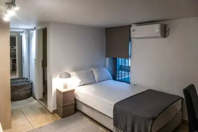 a small bedroom with a bed and a lamp at Varkiza Minimal Residence-5minSea in Vari