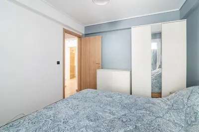 a bedroom with a bed with a blue blanket at VARKIZA APARTMENT in Varkiza