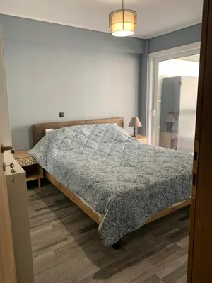 a bedroom with a bed with a gray comforter at VARKIZA APARTMENT in Varkiza
