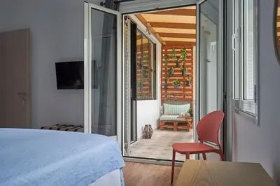 a bedroom with a bed and a chair and a balcony at The sunny house in Athens