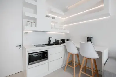 a kitchen with white cabinets and white stools at Nsplace in Athens