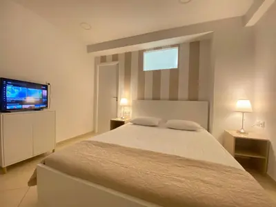a bedroom with a bed and a flat screen tv at Cozy apartment near Airport in Koropíon