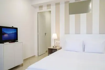 a white bedroom with a bed and a television at Cozy apartment near Airport in Koropíon