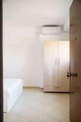 a room with a white bed and a white cabinet at Cozy apartment near Airport in Koropíon