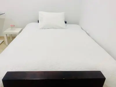 a large white bed with a wooden box at the end at Cozy apartment near Airport in Koropíon