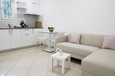 a white living room with a couch and a table at Cozy apartment near Airport in Koropíon