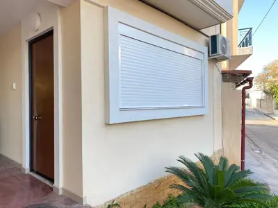 a window with a blind on the side of a house at Cozy apartment near Airport in Koropíon
