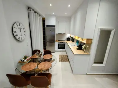 a kitchen with a table and chairs and a clock on the wall at Floral Home 1 - ground floor apt, private parking! in Athens