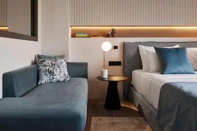 a bedroom with a bed and a chair and a table at Acropolis Grand Suite in Athens