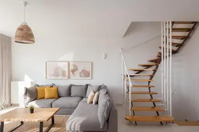 a living room with a couch and a spiral staircase at Athenian Riviera Panorama Villa in Athens