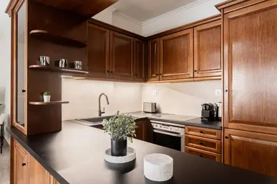 a kitchen with wooden cabinets and a black counter top at Faliro Sunlit 3BR Apartment by UPSTREET in Athens