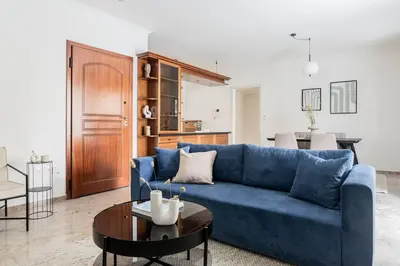 a living room with a blue couch and a table at Faliro Sunlit 3BR Apartment by UPSTREET in Athens