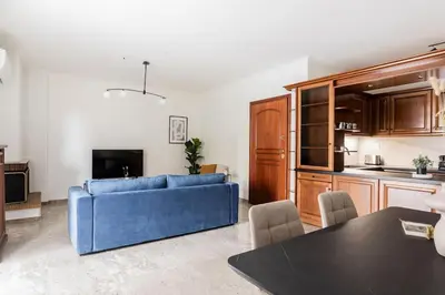 a living room with a blue couch and a kitchen at Faliro Sunlit 3BR Apartment by UPSTREET in Athens