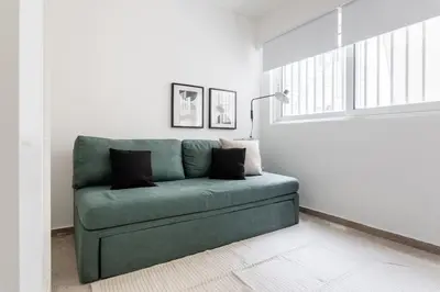 a green couch in a white room with a window at Faliro Sunlit 3BR Apartment by UPSTREET in Athens