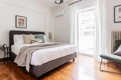 a bedroom with a large bed and a chair at Faliro Sunlit 3BR Apartment by UPSTREET in Athens