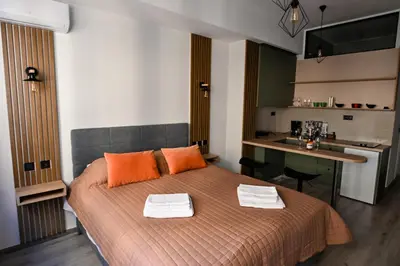a bedroom with a bed with orange pillows and a kitchen at Athinas Relax G1 in Athens