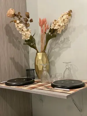 a table with two black plates and a vase of flowers at Aiolos apartment alimos centre 4 near the sea in Athens
